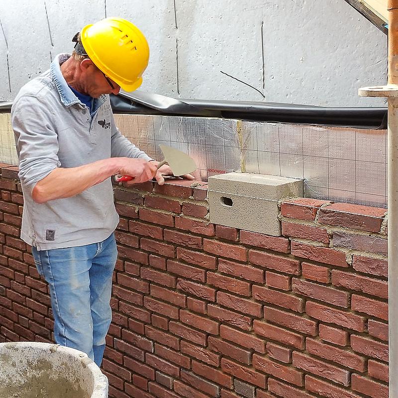 Afbeelding van een man die een inbouwsteen van vivara Pro voor de gierzwaluw inbouwt