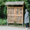 IP WA 02 Insectenwand | 5 Insectenwand op een bedrijventerrrein. Een oudere dame met een grijze jas kijkt naar de insectenwand van Vivara Pro.